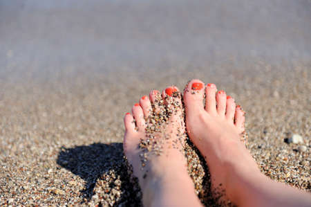 Vacation holidays. Woman feet closeup of girl relaxing on beachの写真素材