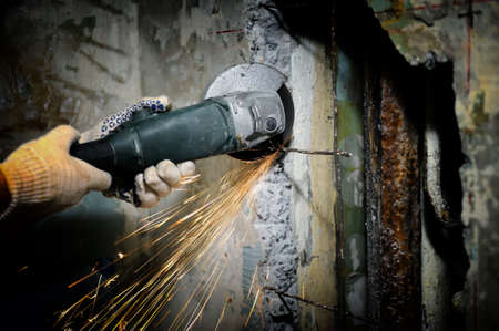 Worker cutting metal with grinder. Sparks while grinding iron