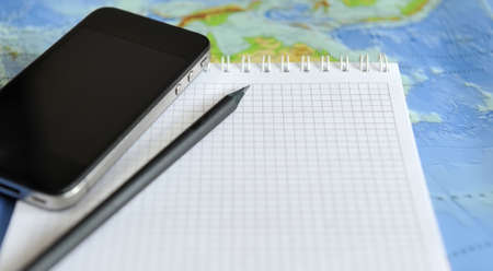 Notebook and phone on a background map of the world. Traveling conceptの写真素材