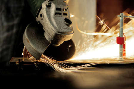 Worker cutting metal with grinder. Sparks while grinding iron