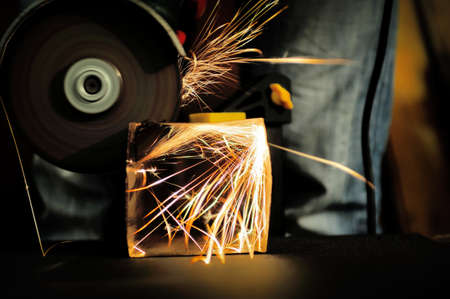 Worker cutting metal with grinder. Sparks while grinding ironの写真素材