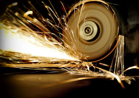 Worker cutting metal with grinder. Sparks while grinding ironの写真素材