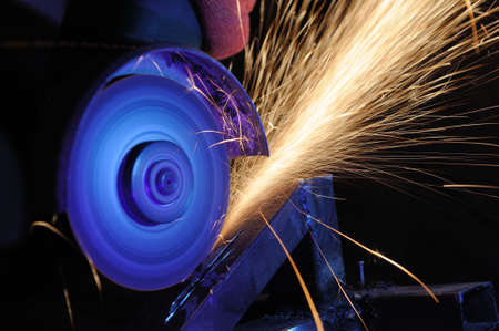Worker cutting metal with grinder. Sparks while grinding iron