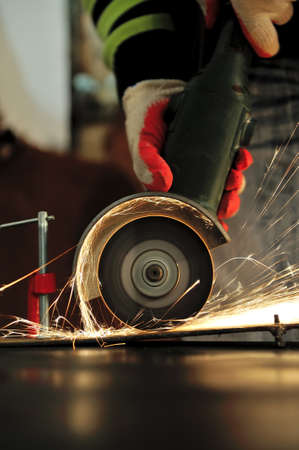 Worker cutting metal with grinder. Sparks while grinding ironの写真素材