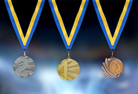 Gold, silver and bronze medals in the foreground with yellow blue ribbonの写真素材