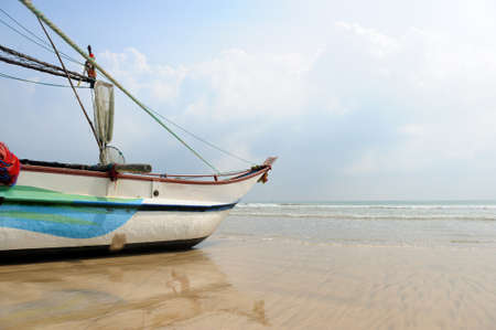 Fishing boats resting on empty beach in Sri Lankaの写真素材