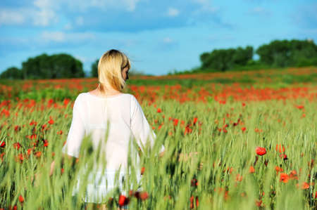 Young beautiful girl in the poppy and wheat fieldの写真素材