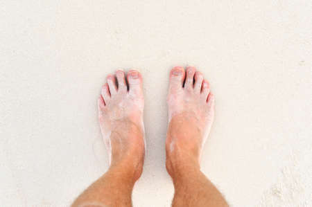 Man's legs on the white sand Indian ocean
