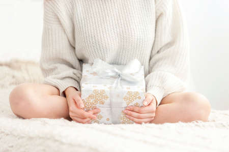 Woman sits on the bed and holding a giftの写真素材