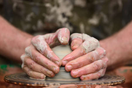 Hands of a potter. Potter making ceramic pot on the pottery wheelの写真素材