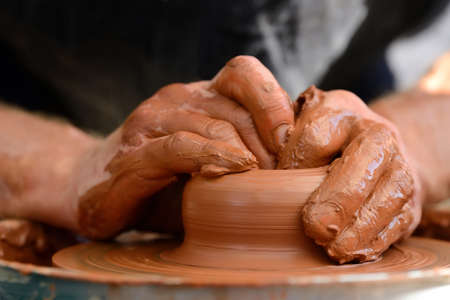 Hands of a potter. Potter making ceramic pot on the pottery wheelの写真素材