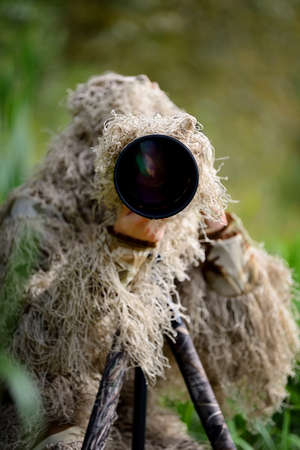 Camouflage wildlife photographer in the ghillie suit working in the wildの写真素材