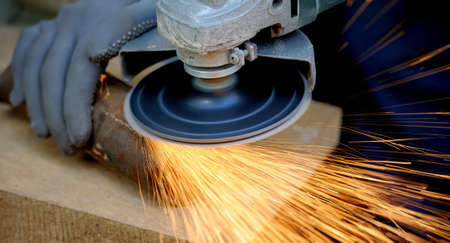 Worker cutting metal with grinder. Sparks while grinding iron