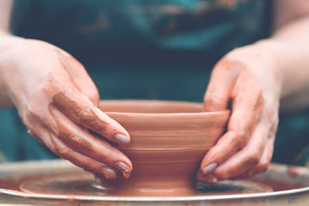 Hands of a potter. Potter making ceramic pot on the pottery wheelの写真素材