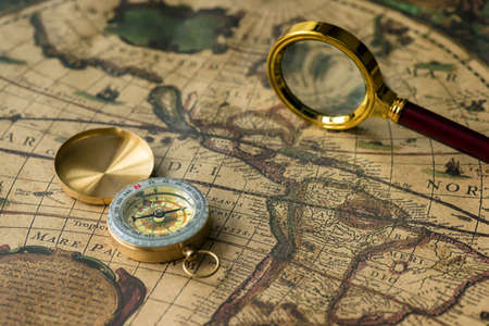 Retro compass with old map and magnifier closeup