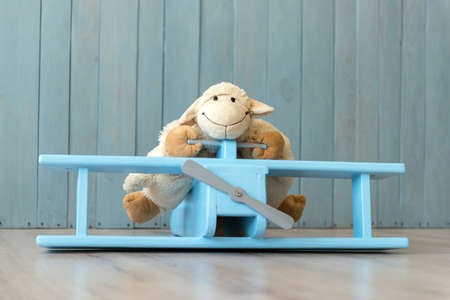 Wooden retro airplane model and sheep toy over retro vintage brown background. Toys from wood