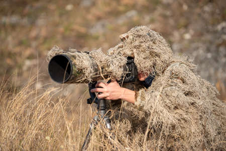 Camouflage wildlife photographer in the ghillie suit working in the wildの写真素材