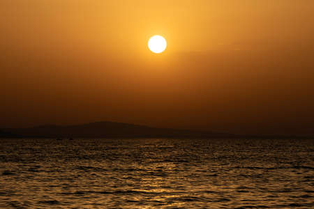 Bright sunset with large yellow sun the sea surface