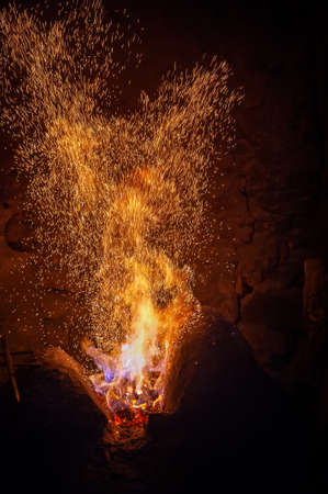 Burning red hot sparks fly from big fire. Abstract dark background