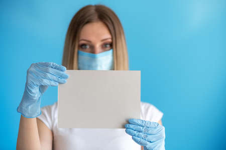 Young nurse or doctor showing empty blank sign board with copy space in hand. Focus on a piece of...