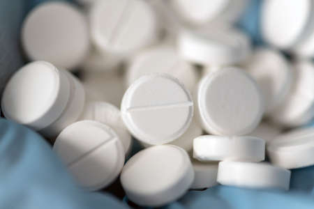 Closeup doctor or nurse hands in blue rubber gloves with handful pills. Medicine concept