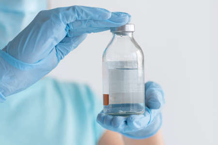 Bottle for injection in nurse hand. Medical glass vial for vaccination. Science equipment, liquid...