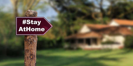 Direction board with an message Stay at home with blurred house background. Corona virus outbreakingの写真素材