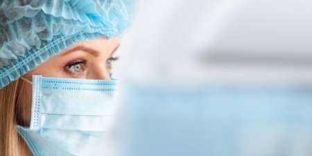 Surgical Nurse or doctor with face mask and cap. Health care, surgery. Close up portrait of young caucasian woman model on white backgroundの写真素材