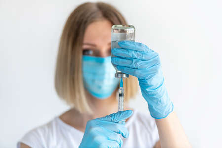 Bottle and syringe for injection in nurse hand. Medical glass vial for vaccination. Science equipment, liquid drug or vaccine. Medicine conceptの写真素材