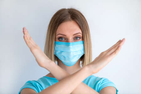 Attractive female nurse showing stop sign with his hand gesture isolated on white background. Medical concept of infectionの写真素材