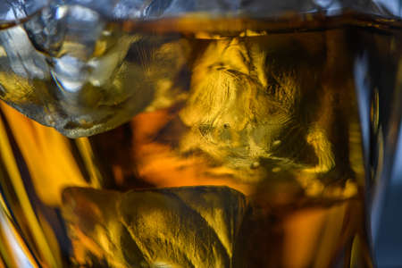 Pieces of ice cube in whiskey. Close up macro of Ice cubes in glass drink or another alcohol. Abstract texture backgroundの写真素材