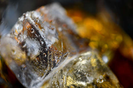 Pieces of ice cube in whiskey. Close up macro of Ice cubes in glass drink or another alcohol. Abstract texture backgroundの写真素材