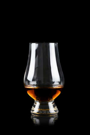 Glass of whiskey or other alcohol on black background