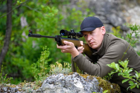 Close male with a gun in hunting period. Hunter in camouflage clothes nature backgroundの写真素材