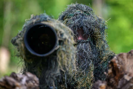 Wildlife photographer in the summer ghillie camouflage suit working in the wildの写真素材
