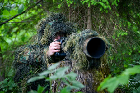 Wildlife photographer in the summer ghillie camouflage suit working in the wildの写真素材