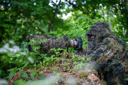 Wildlife photographer in the summer ghillie camouflage suit working in the wildの写真素材