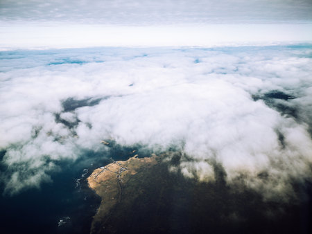 Landscape seen from plane of the island of Iceland with clouds, land and sea in partly cloudy day.の写真素材