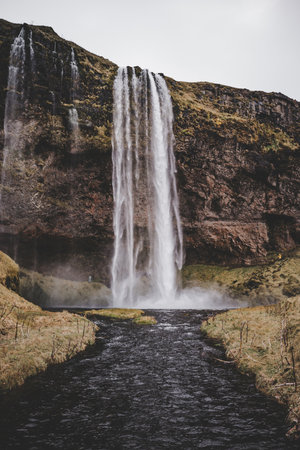 Waterfall landscape in Iceland in October with brown green colors and black earthの写真素材