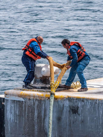 Puerto Madryn, Argentina - December 13, 2012: On the mooring platform a workers casts off the...