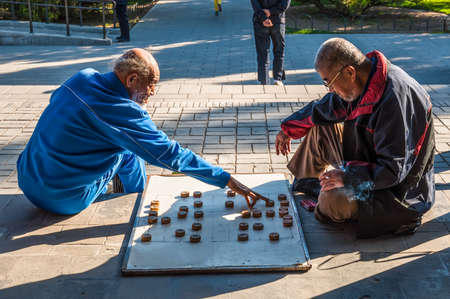 Beijing, China - October 15, 2013: Elderly Chinese men playing Chinese chess called Xiangqi in a park outside the Temple of Heaven, Beijing, China. It is a very popular in China strategy board game for two players.のeditorial素材