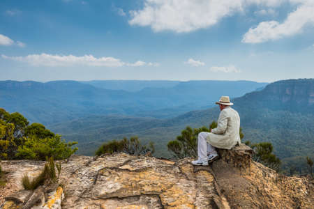 Sydney, Australia - November 10, 2014: The imposing man in a hat sitting on the edge of a cliff...