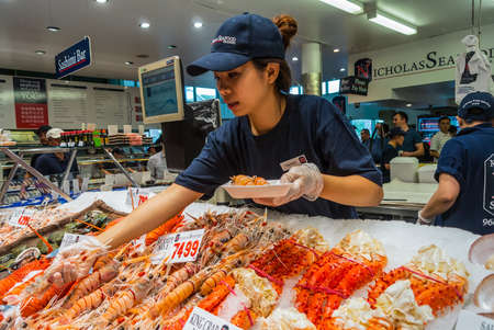 Sydney, Australia - November 11, 2014: Vendor preparing seafood for a buyer in Famous Sydney Fish Market, Sydney, New South Wales, Australia.のeditorial素材