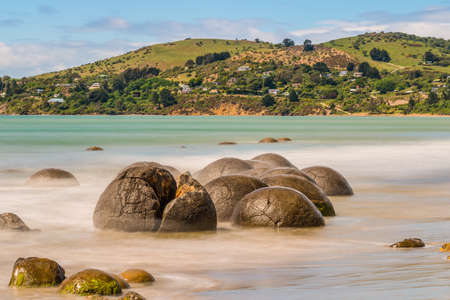 Long exposure image of Moeraki Boulders lying along a stretch of Koekohe Beach on the wave-cut Otago coast of South Island New Zealand. These formations are a major tourist attraction of the area.の写真素材