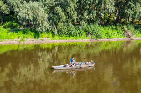 Chernihiv, Ukraine - August 28, 2016: A fisherman in a wooden boat on the Desna river in the...