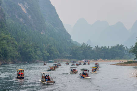 Yangshuo, China - October 20, 2013: Many Bamboo Rafts on the Li river in the haze near Yangshuo, China.のeditorial素材