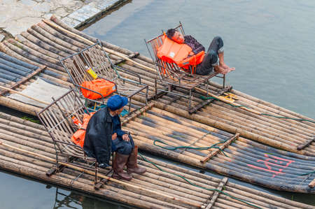 Yangshuo, China - October 20, 2013: Boaters rest waiting for tourists on their bamboo raft on the bank of the Li River, Yangshuo, China.のeditorial素材