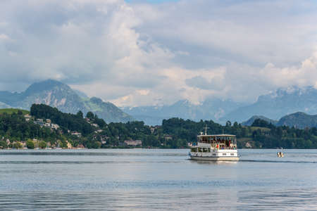 Lucerne, Switzerland - May 24, 2016: Cruise passenger boat in front of hidden by clouds snow covered Alps mountains peaks on Lake Lucerne, Switzerland.のeditorial素材