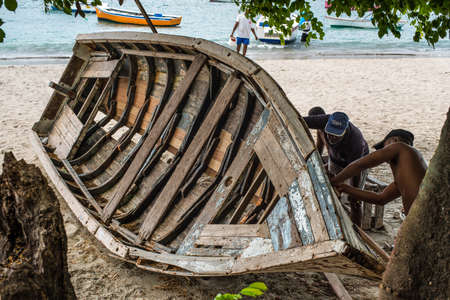 Tamarin, Mauritius - December 8, 2015: Unidentified villagers repair wooden boat on shore at Tamarin Bay in Mauritius.のeditorial素材