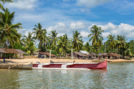 Ambatozavavy, Nosy Be, Madagascar - December 19, 2015: Traditional wood pirogue and a modern boat with outrigger on the shore of the fishing village on the Nosy Be island, Madagascar.のeditorial素材